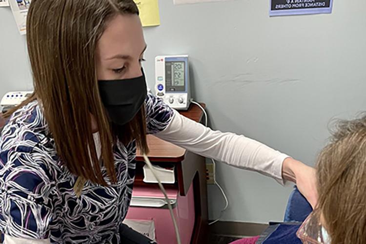 UMKC药学院的学生劳伦·达蒙在汉尼拔免费诊所给病人量血压.